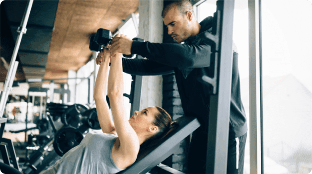 A man in a gym lifting dumbbells with focus.