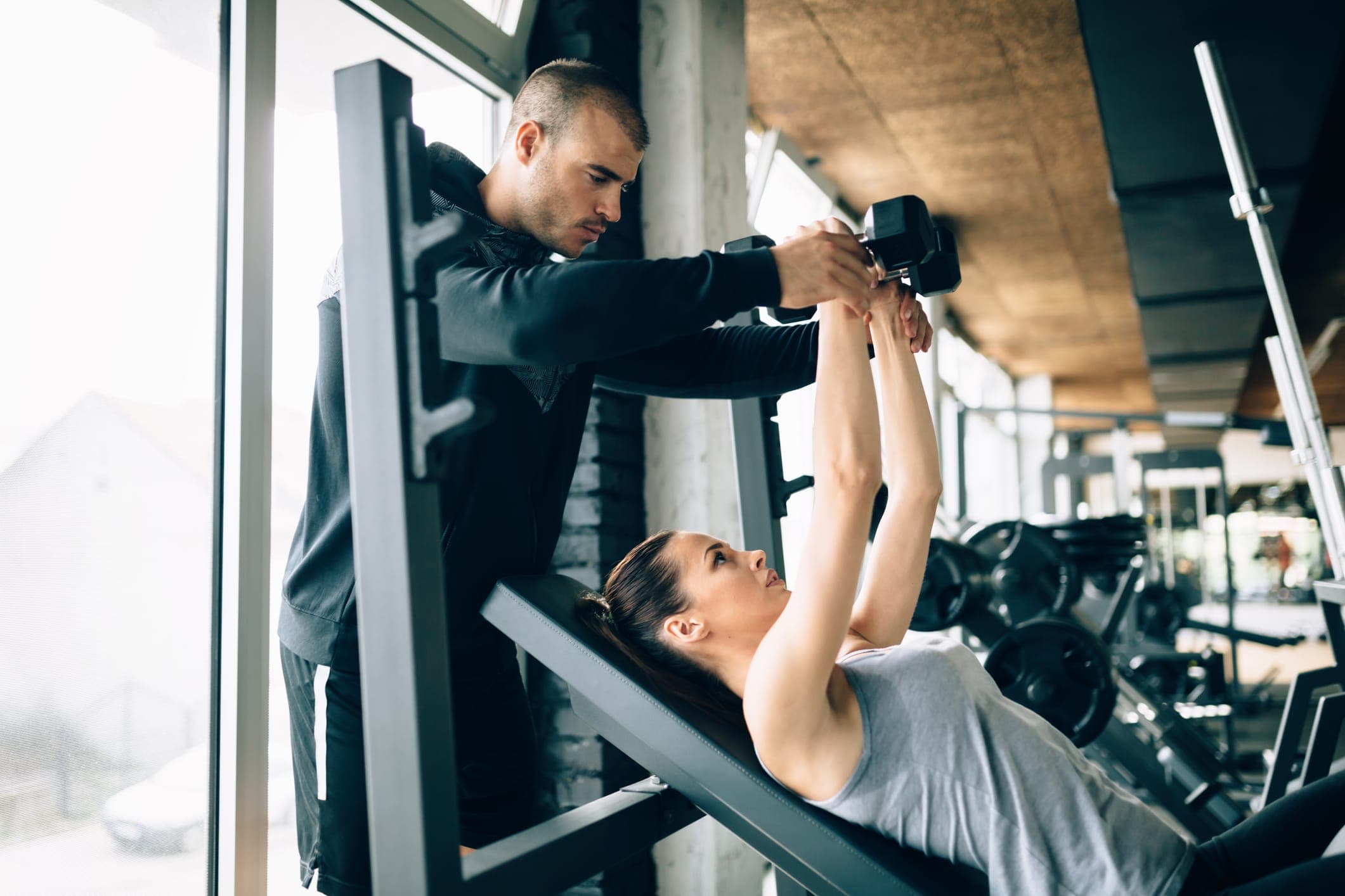 A man in a gym lifting dumbbells with focus.